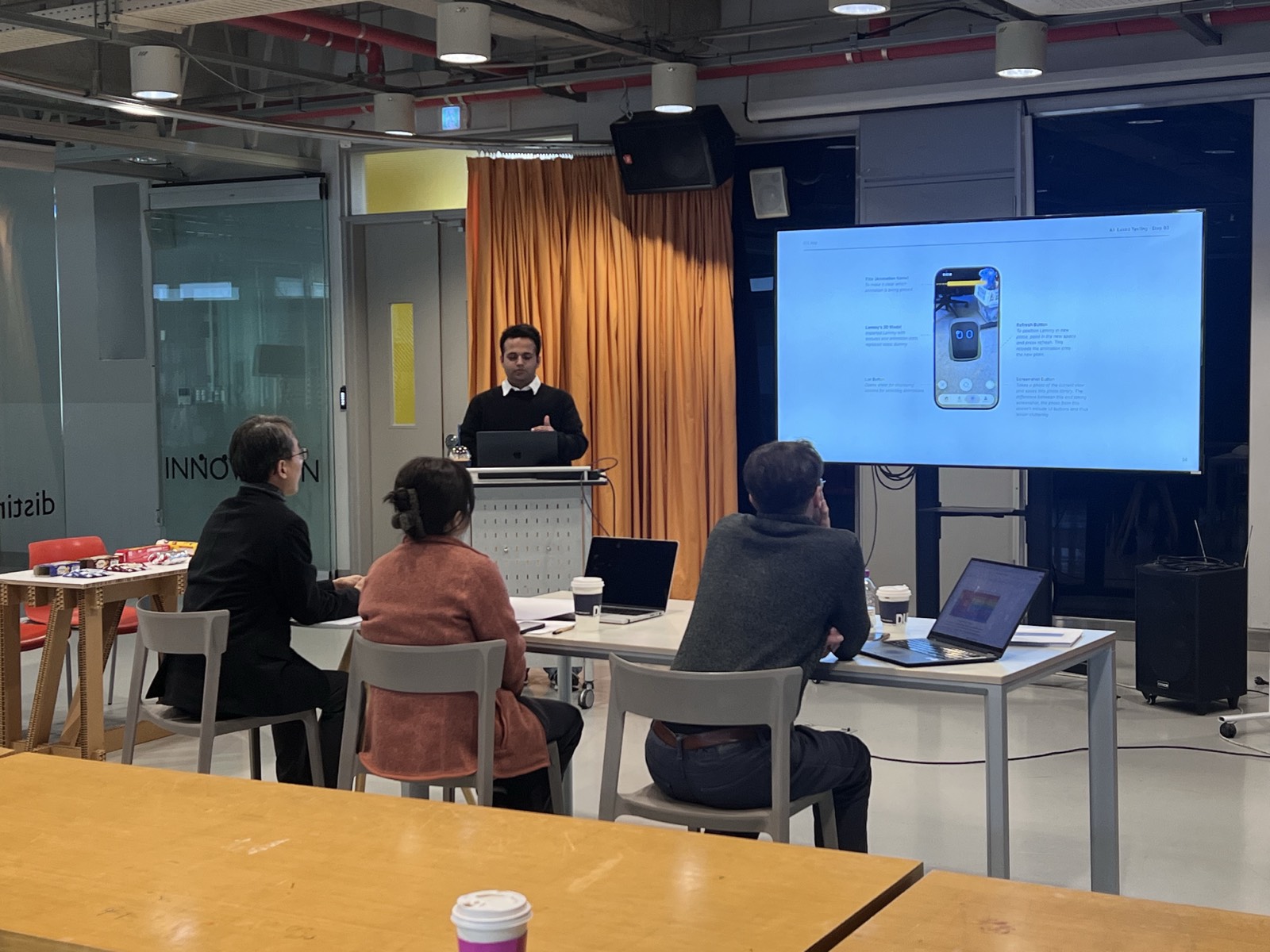 Danyal presenting a slide about the AR page of the Lemmy app to three seated reviewers