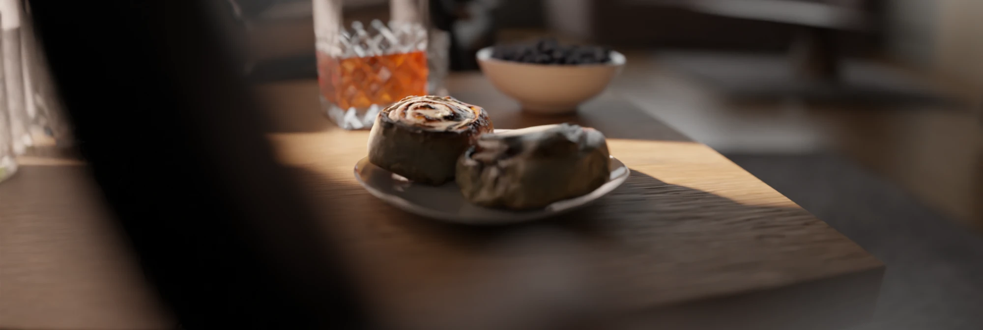 Cinnamon rolls on a plate in a strip of sunlight, with the decanter and a bowl of blueberries behind