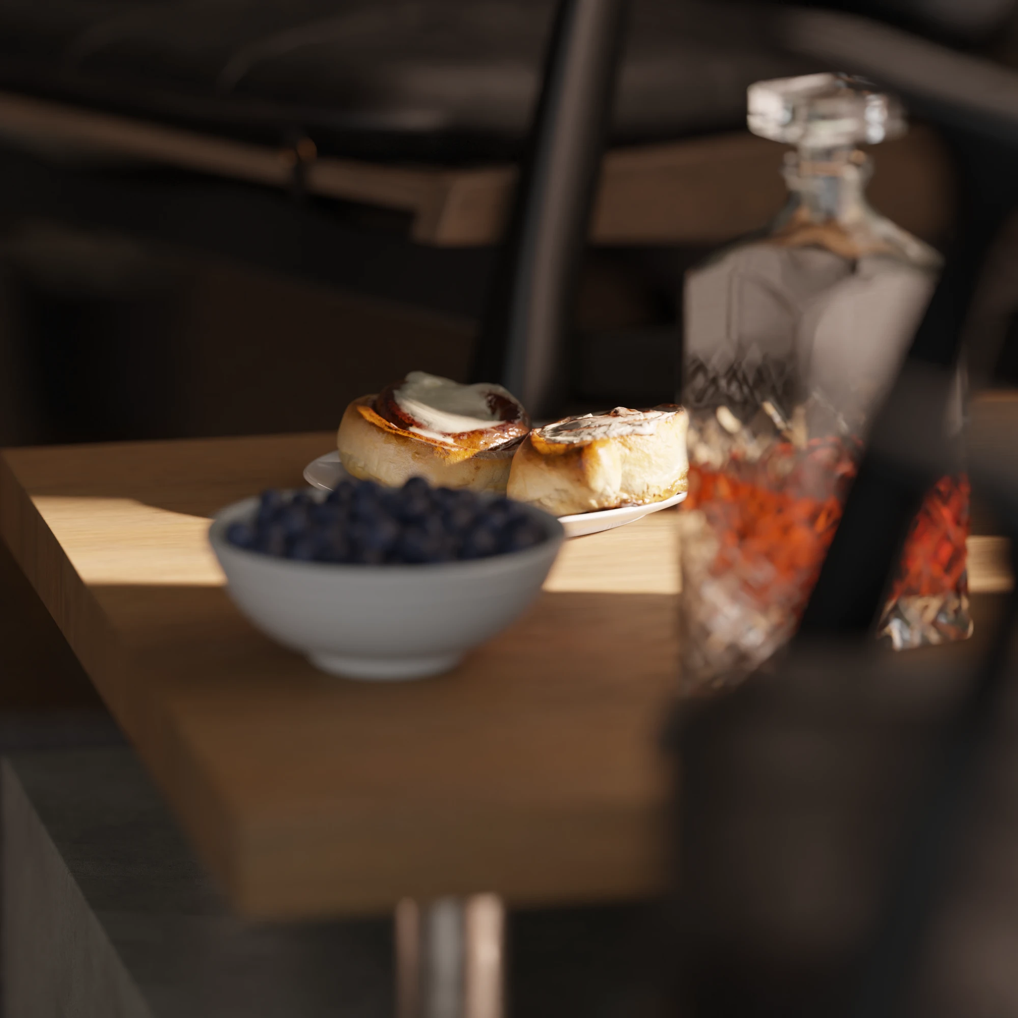 Cinnamon rolls and a bowl of blueberries on the table, the decanter out of focus in front