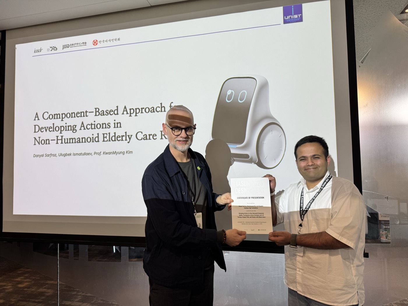 Danyal receiving a presenter certificate in front of a slide about component-based robot actions
