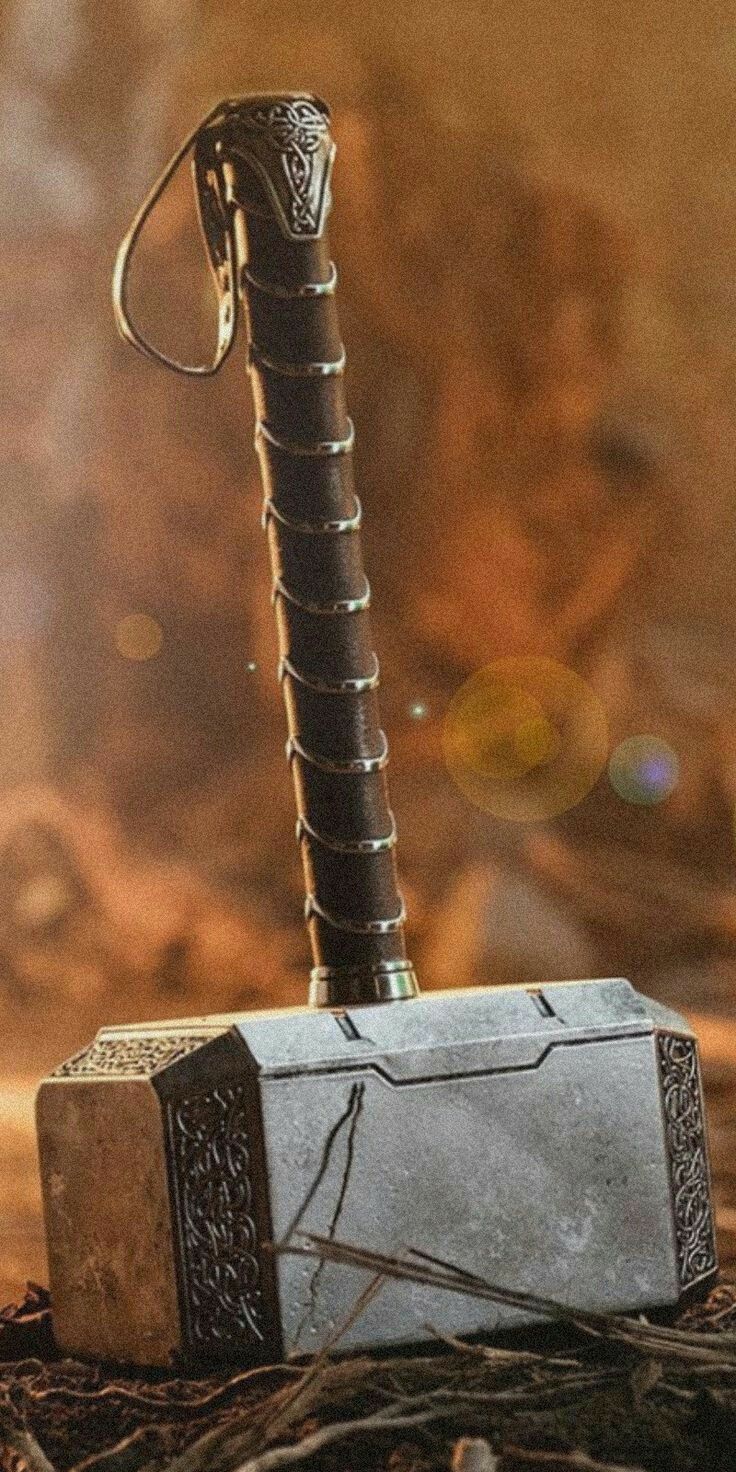 Mjölnir standing on its head in dirt, its leather strap looped at the top