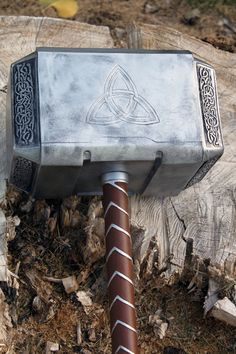 A silver replica of Mjölnir resting on a tree stump